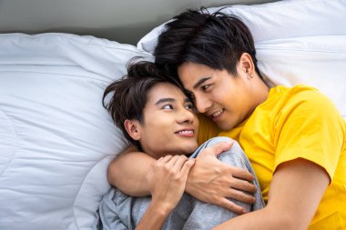 Mutlu Asyalı homoseksüel erkek eşcinsel çift yatakta uzanıyor ve kucaklaşıyorlar. LGBT ve cinsel çeşitlilik kavramı.