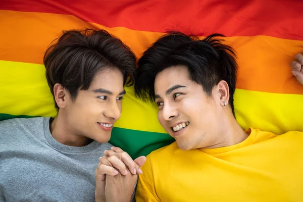 幸せなアジアの同性愛者のカップル虹の誇りフラグに横たわって 手を握って Lgbtの概念 — ストック写真