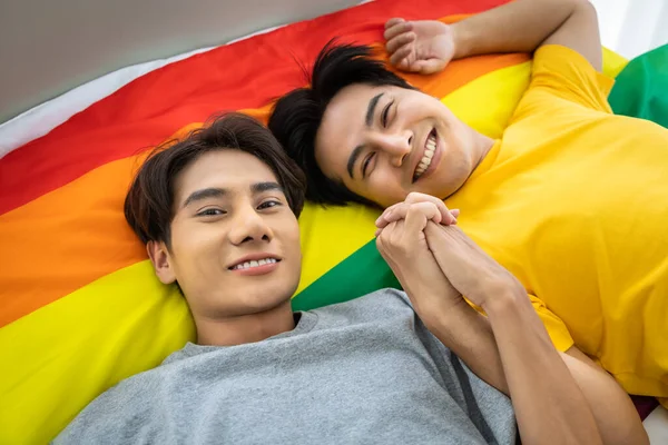 幸せなアジアの同性愛者のカップル虹の誇りフラグに横たわって 手を握って Lgbtの概念 カメラを見ると — ストック写真