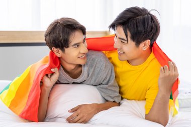 Mutlu Asyalı eşcinsel çift gökkuşağı gurur bayrağı altında yatar, LGBT konsepti.
