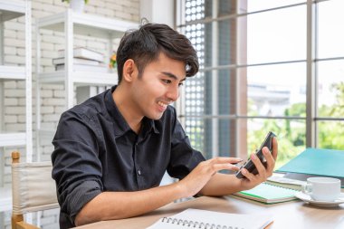 Genç Asyalı işadamı yemek odasında hesap makinesi ve planlama kullanarak çalışıyor..