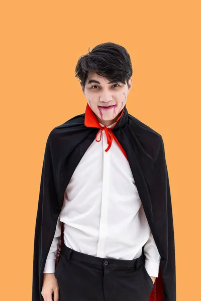 Asiatischer Mann Halloween Kostüm Als Vampir Dracula Auf Orangefarbenem Hintergrund lizenzfreie Stockfotos