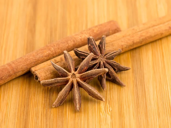 Anise estrellas y palo de canela en tablero de madera —  Fotos de Stock