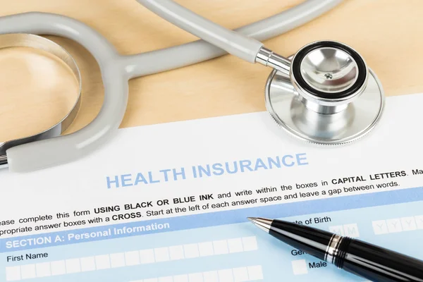 Sjukförsäkring ansökningsblankett med penna och stetoskop conce — Stockfoto