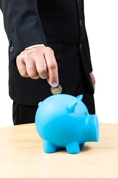 Empresário colocando moeda no banco porquinho azul no backgroun branco — Fotografia de Stock