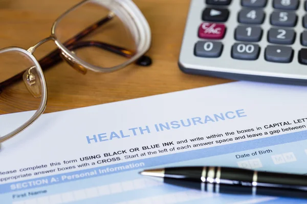 Health insurance application form with pen, calculator, and glas — Stock Photo, Image