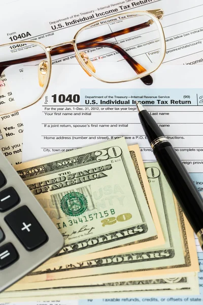 Налоговая форма с ручкой, калькулятором, банкнотой в долларах и налогом на очки — стоковое фото