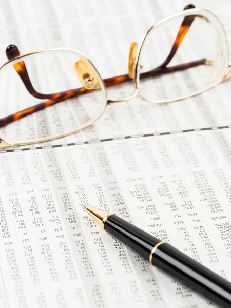 Stylo et lunettes reposent sur le détail du cours de l'action journal financier — Photo