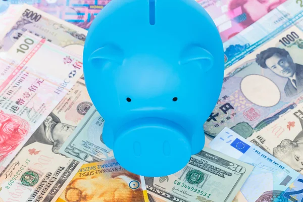 Blue piggy bank on international banknote background — Stock Photo, Image