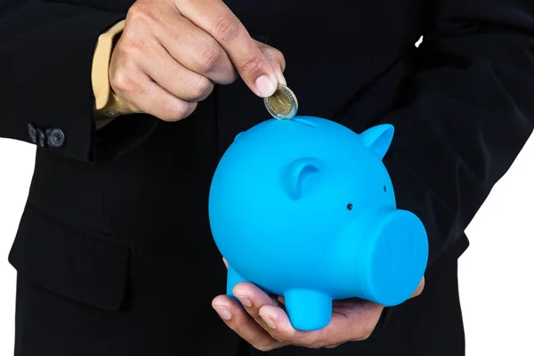 Empresário colocando moeda no banco porquinho azul no backgroun branco — Fotografia de Stock