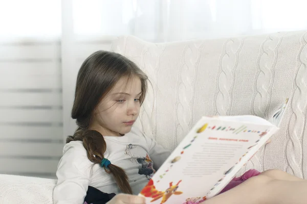 Έφηβος κορίτσι διαβάζει ένα βιβλίο, ενώ κάθεται σε μια καρέκλα — Φωτογραφία Αρχείου