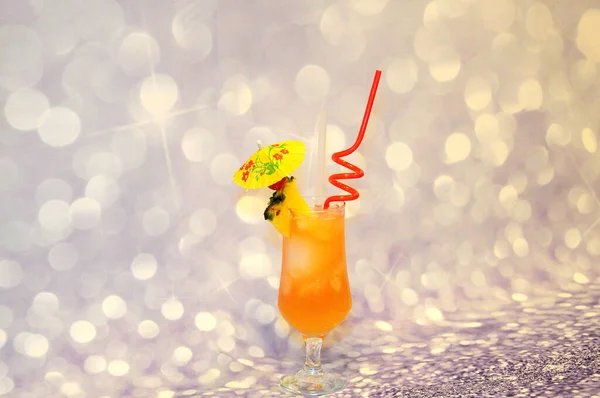 A glass of Pina Colada cocktail with a slice of pineapple, cherry, straws and a cocktail umbrella stands on a gray shiny background. Close-up.