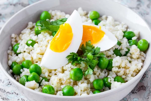 Bulgur, rice with green peas and boiled egg yolk, spring, summer — Stock Photo, Image