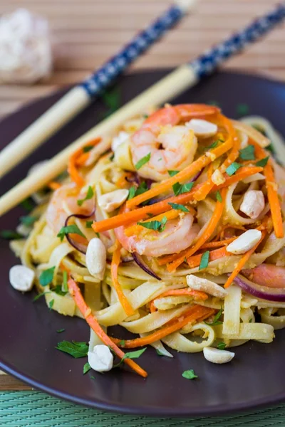Asijské nudle s krevetami, zelenina, mrkev, arašídy, cibule, — Stock fotografie