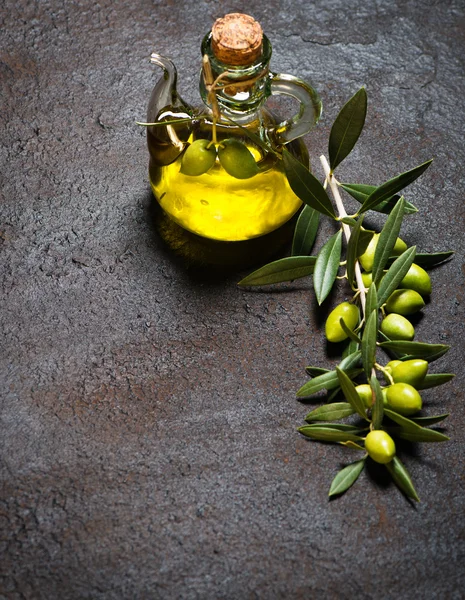 Glass bottle of virgin olive oil and branch with olives — Stock Photo, Image