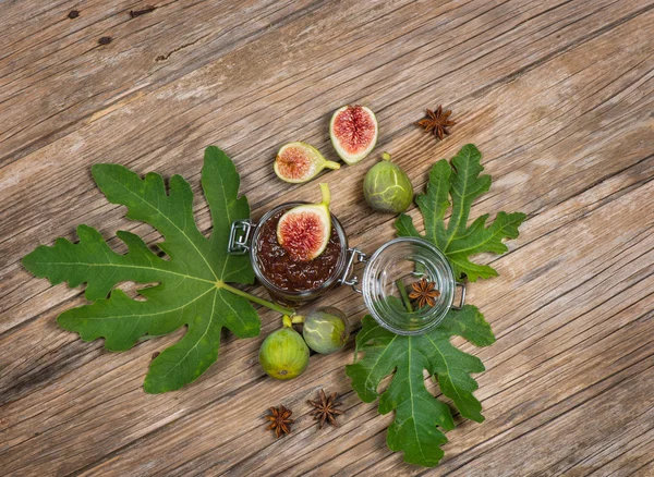 Uitzicht vanaf boven van vijgen op vijgenblad en jam op houten tafel — Stockfoto