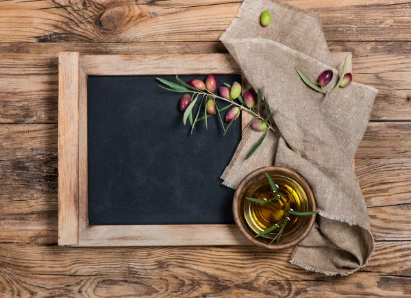 Aceitunas y aceite de oliva con tablero de menú - ambiente rústico —  Fotos de Stock