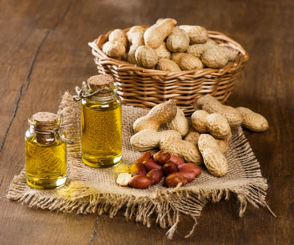 Arašídový olej a ořechy na dřevěný stůl — Stock fotografie
