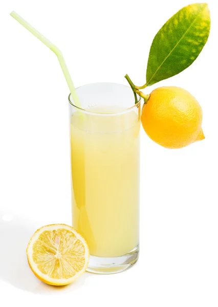 Glass of lemon juice and fruit with leaves — Stock Photo, Image