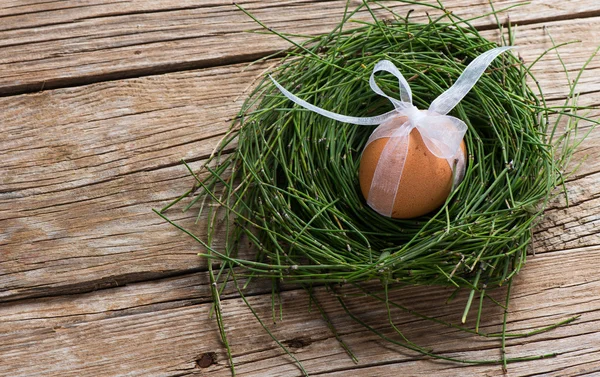 Easter egg with ribbon in a nest — Stock Photo, Image