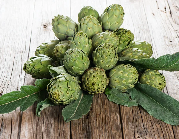 Natuurlijke artisjokken over donkere houten tafel — Stockfoto