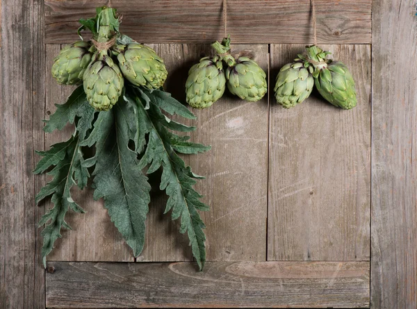 Raw artichokes on a aged table — Stock Photo, Image