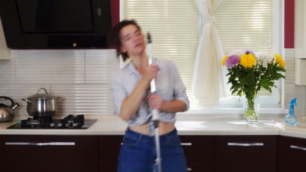 Молода дівчина домогосподарка в веселому настрої прибирає кухонні танці і співає з мопедом. 4k — стокове відео