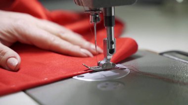 Kırmızı dokumayla çalışan usta bir terzinin kadın elleri.