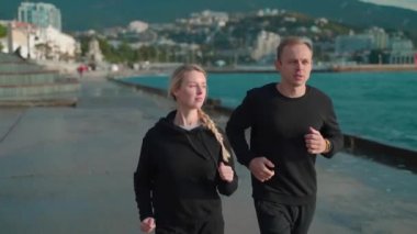 Spor giyimli genç bir çift deniz kenarında sabah koşusuna çıkıyor. Erkek ve kız birlikte spor yapmaya gidiyorlar. Deniz kenarından setin kenarına doğru koşuyorlar..