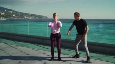 Genç bir adam bir kızı spor yapmaya zorluyor, etrafında koşup ona bağırıyor. Adam saldırganca kıza egzersizleri doğru yapmayı öğretiyor. 4k