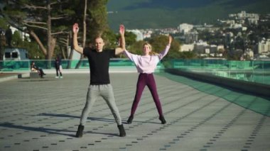 Spor giyimli genç bir çift sabah egzersizlerinde denizin arka planına karşı çarpışırlar. Erkek ve kız birlikte spor yapmaya gidiyorlar. 4k