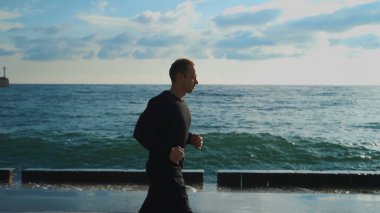 Sabahın erken saatlerinde genç bir adam deniz fenerinin arka planında koşu yapmakla meşgul..