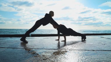 Spor giyimli genç bir çift sabah egzersizlerinde denizin arka planına karşı çarpışırlar. Erkek ve kız birlikte spor yapıyorlar..