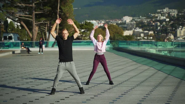 Spor giyimli genç bir çift sabah egzersizlerinde denizin arka planına karşı çarpışırlar. Erkek ve kız birlikte spor yapıyorlar..