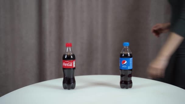 러시아 얄타, 2020 년 11 월 29 일 - 펩시 vs 코카 콜라. 반 리터짜리 펩시와 코카 콜라 병을 테이블 위에 놓고 여학생이 코카 콜라를 선택하는 모습. — 비디오