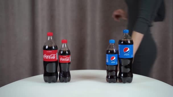 Jalta, Rusko, 29-November-2020-Pepsi vs Coca Cola. Jeden litr a půl litru láhve Pepsi a Coca Cola na stole dívka vybere Pepsi. — Stock video