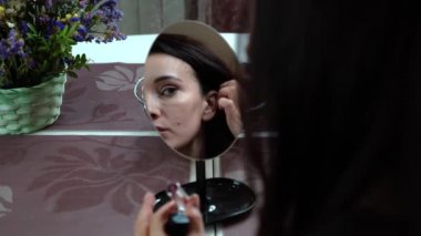 Masadaki kız küçük bir aynada yansımasına bakar ve dudaklarını rujla boyar ve kendinden memnun olur.