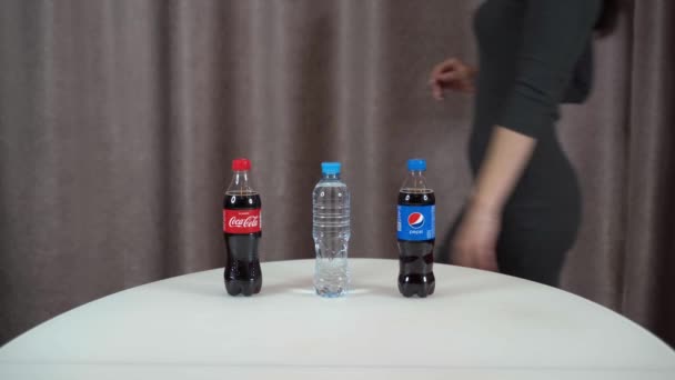 Jalta, Ryssland, 29-November-2020-Rent dricksvatten mot Coca Cola och Pepsi. Det finns tre flaskor med olika drycker på bordet, flickan väljer vanligt dricksvatten och välter Pepsi — Stockvideo