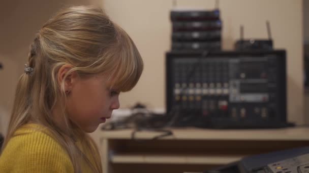 Elektronik piyanonun başındaki küçük kız bir melodi çalmayı öğreniyor.. — Stok video