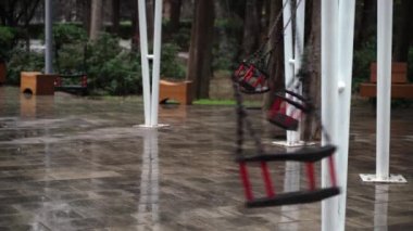 Boş bir parkta salıncak tek başına sallanıyor. Kışın parkta, kötü havada, salıncak kendi kendine sallanıyor..