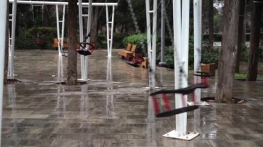 Boş bir parkta salıncak tek başına sallanıyor. Kışın parkta, kötü havada, salıncak kendi kendine sallanıyor..