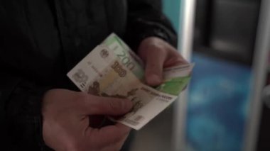 Beyaz bir adam araba yıkamada çalışıyor. İşçi elinde Rus rublesi tutuyor ve maaşını hesaplıyor..