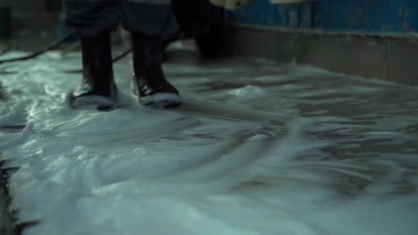 Beyaz bir adam araba yıkamada çalışıyor. Araba yıkama servisi çalışanının botlarındaki ayaklar yerdeki köpük üzerinde yürür. — Stok video
