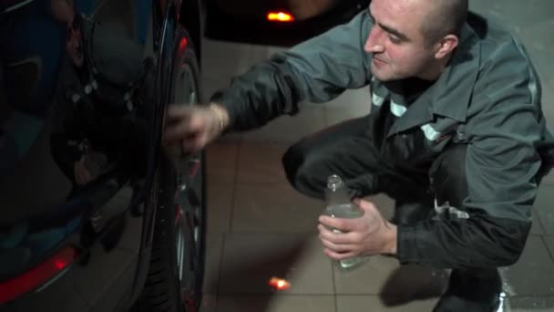 Un hombre caucásico trabaja en un lavado de autos, un trabajador de lavado de autos lava el auto. El empleado de servicio limpia el coche con un trapo — Vídeos de Stock