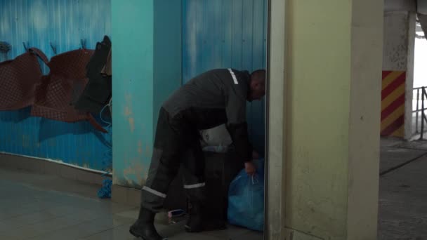 Un uomo di etnia caucasica lavora in un atomizzatore e porta fuori la spazzatura dal lavoro. — Video Stock