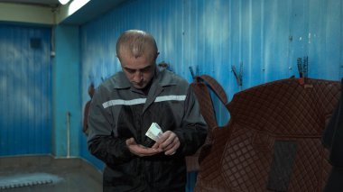 Kafkas uyruklu bir erkek işçi bir iş günü için Rus rublesi aldı. Bir erkek işçi elinde para tutar ve sayar.