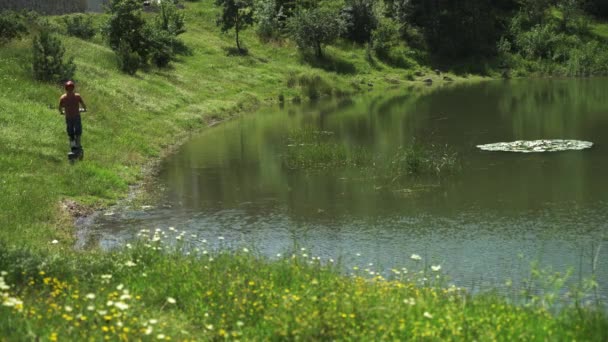 A montar um veículo eléctrico poderoso. Um homem em um capacete de segurança monta o caminho em uma scooter elétrica ao longo do lago da câmera — Vídeo de Stock