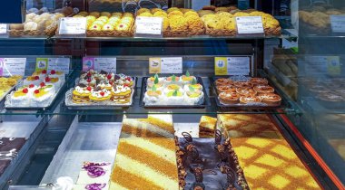 Mağaza vitrininde bol miktarda pasta, pasta ve kurabiye var. Her şey çok iştah açıcı görünüyor..