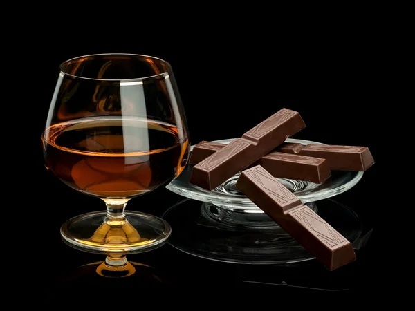 Chocolade en cognac in glaswerk die het is geïsoleerd op zwart Rechtenvrije Stockfoto's