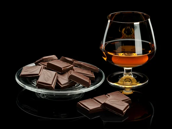 Chocolade en cognac in glaswerk die het is geïsoleerd op zwart Stockfoto